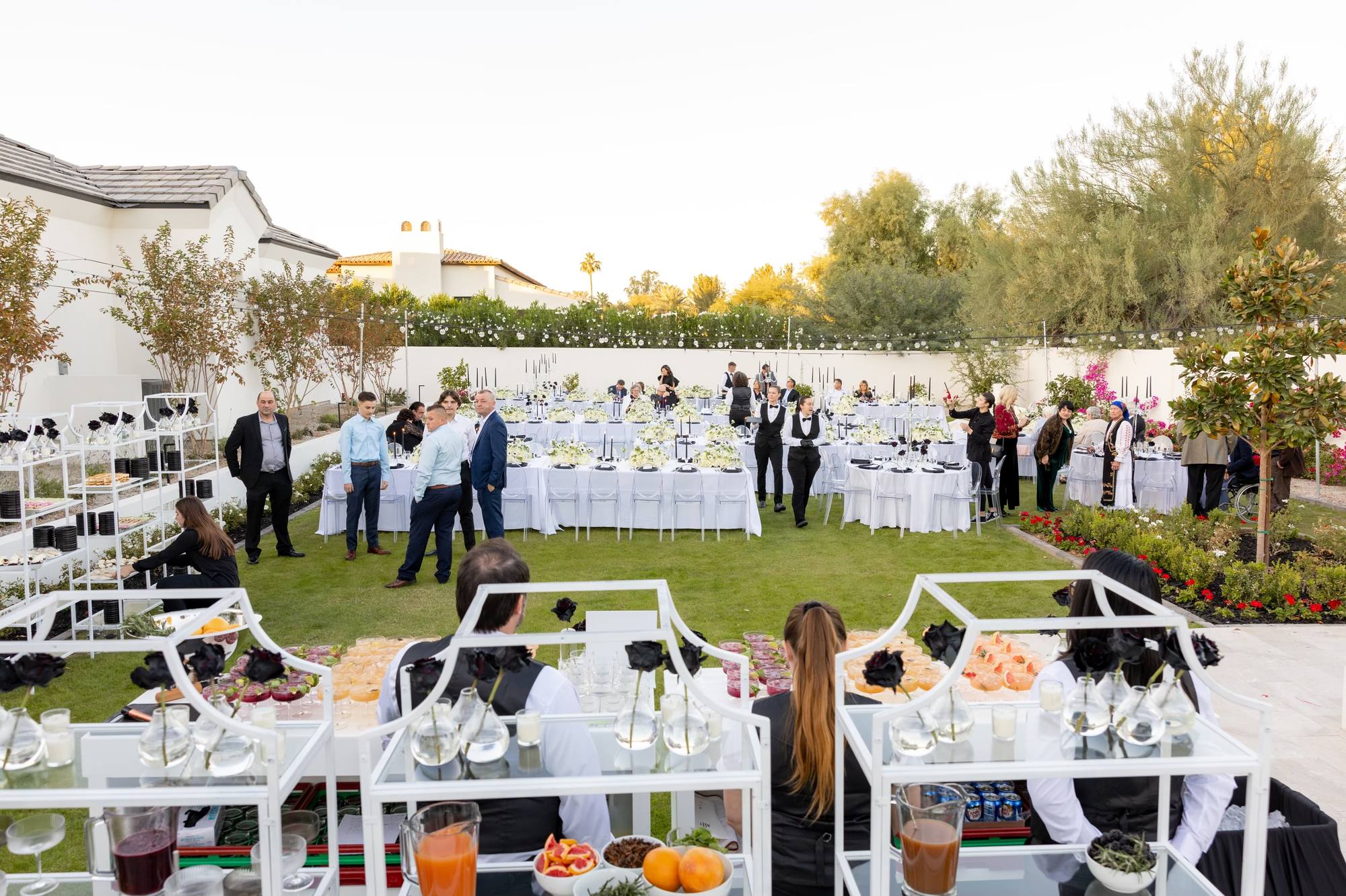 Outdoor estate dinner catered in Chandler, Arizona, with long white banquet tables and bar service at dusk
