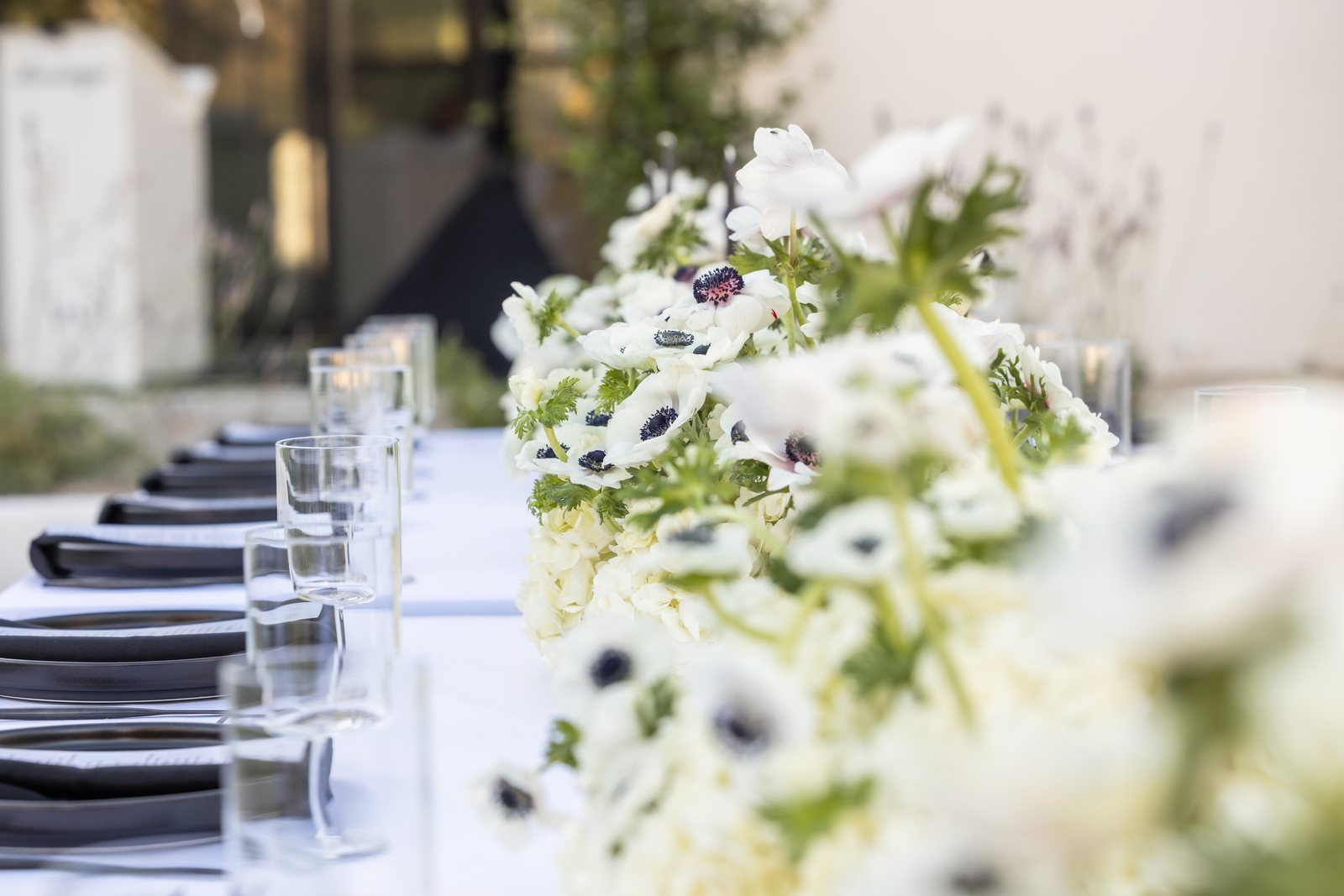 White anemone centerpieces on a long wedding reception table catered in Chandler, Arizona